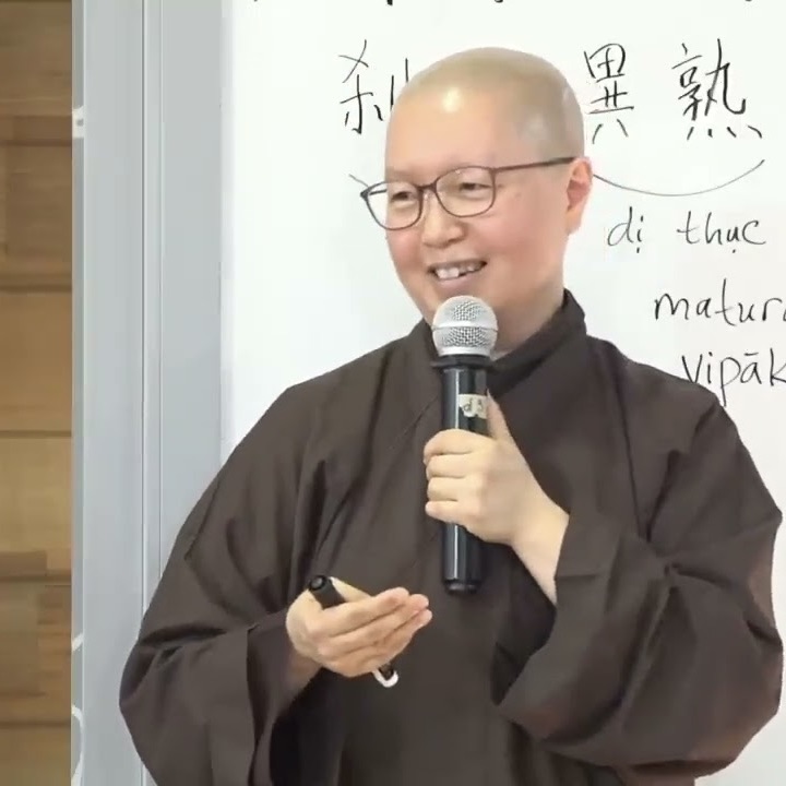 Photo of Sister Lang Nghiem holding a microphone and standing in front of a whiteboard with writing